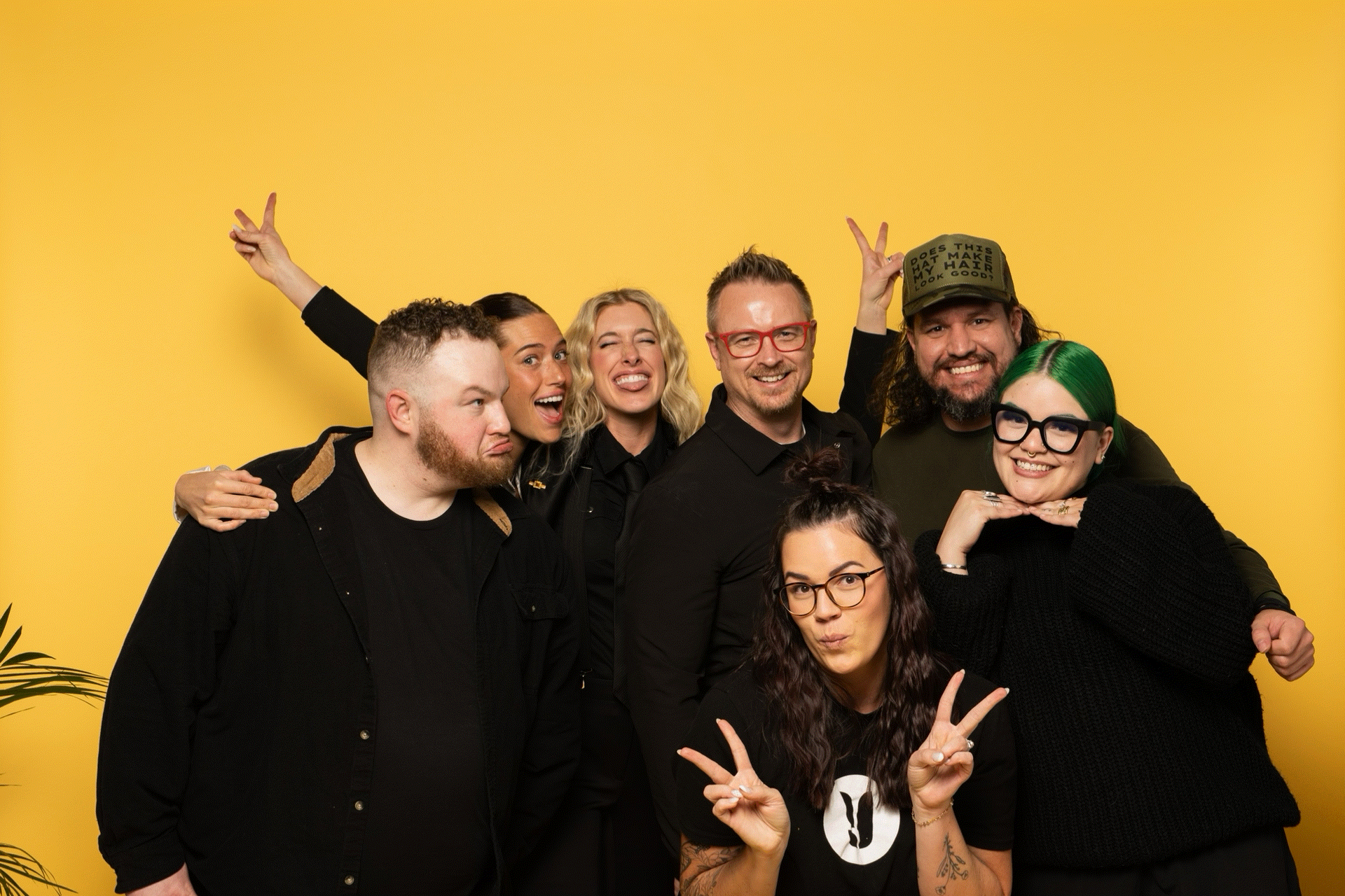 Seven members of the Younique creative team clowning for the camera against a yellow backdrop